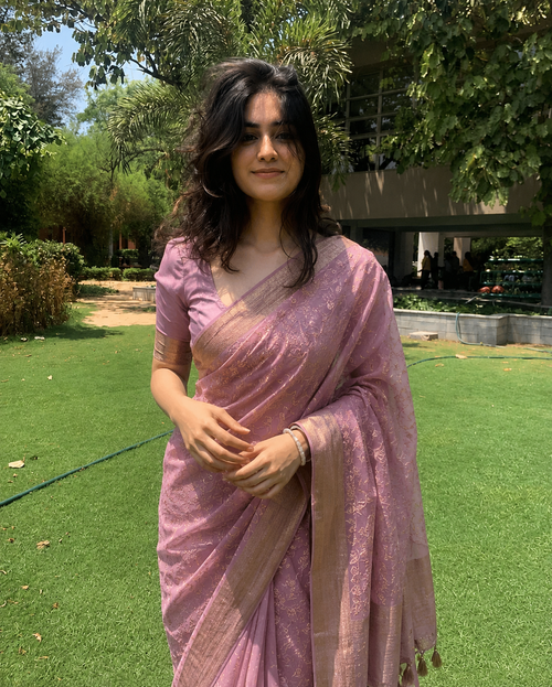 Woman in a pink saree standing in a garden